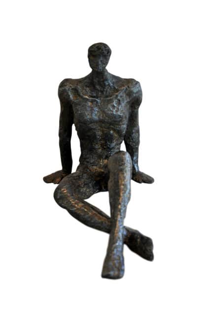 Bronzed sculpture of a seated figure with crossed legs.
