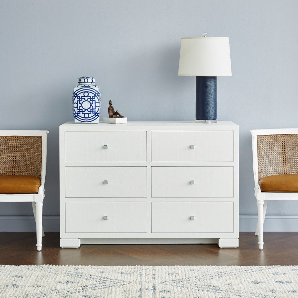 White lacquered grasscloth dresser with six drawers and hand-cast chrome handles in a side view.