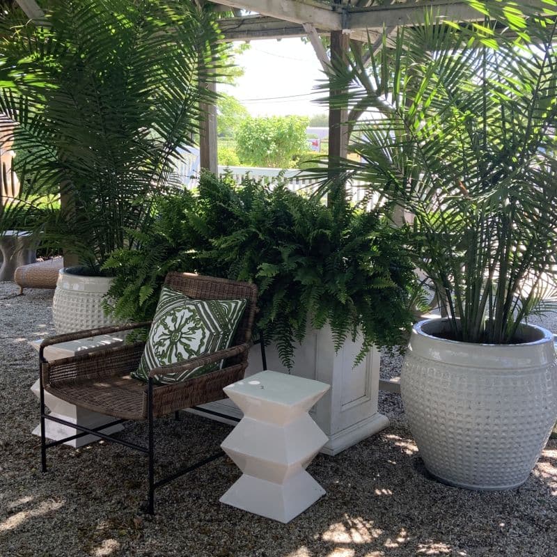 Ceramic zig zag garden stool in garden with potted plants.