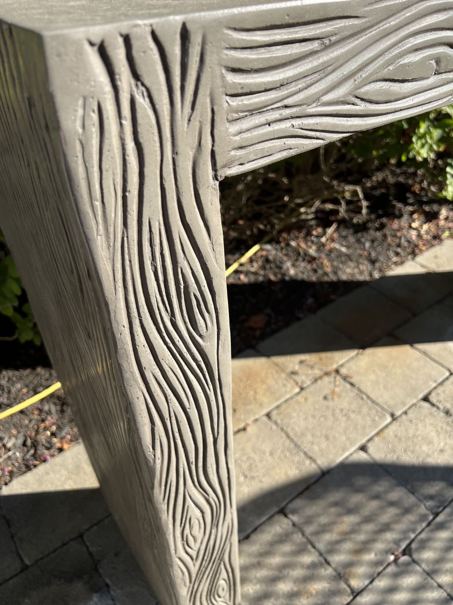 Front view of an outdoor etched concrete Parsons console in dark gray, showcasing intricate faux bois design.