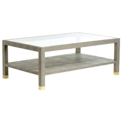 A rectangular coffee table with a faux shagreen top and glass shelves, available in four colors: Blanc, Black, Grey, or Sand.