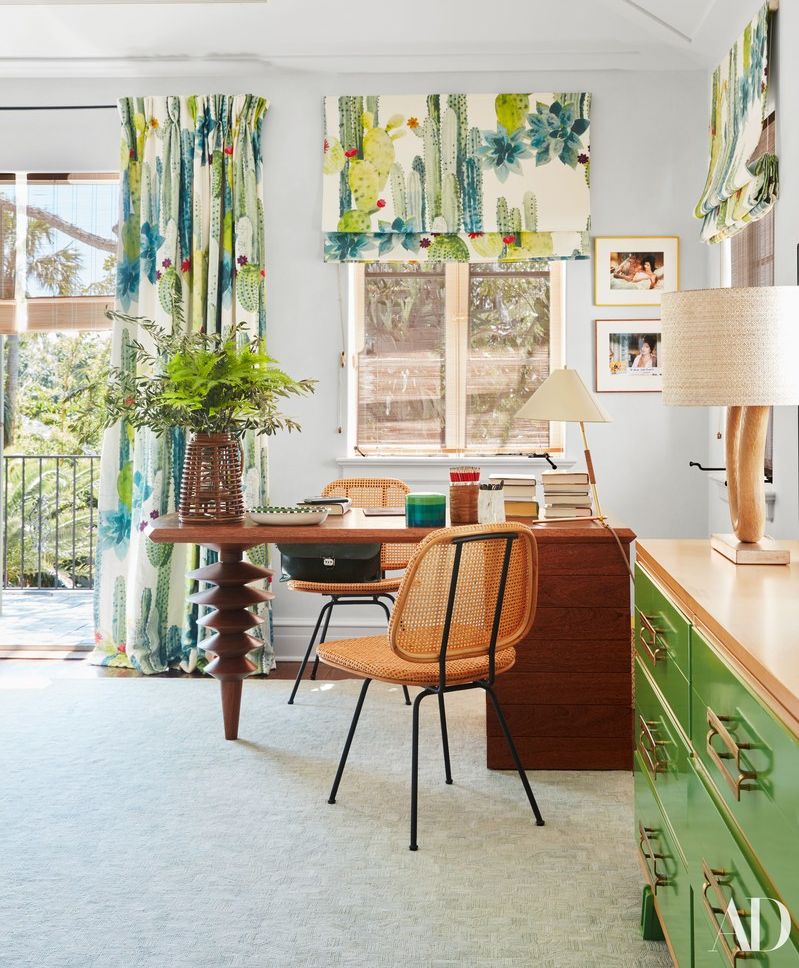 A spacious living room with a large window allowing natural light to flood in featuring a blue and white floral curtain a