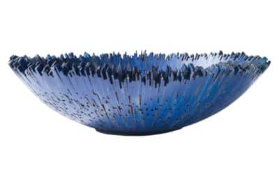 A large colorful bowl with a blue and grey design resembling a piece of art or decorative accessory placed on a white