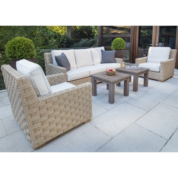 This image features an outdoor seating area with a wicker sofa set which includes a large sofa and two matching armchairs The