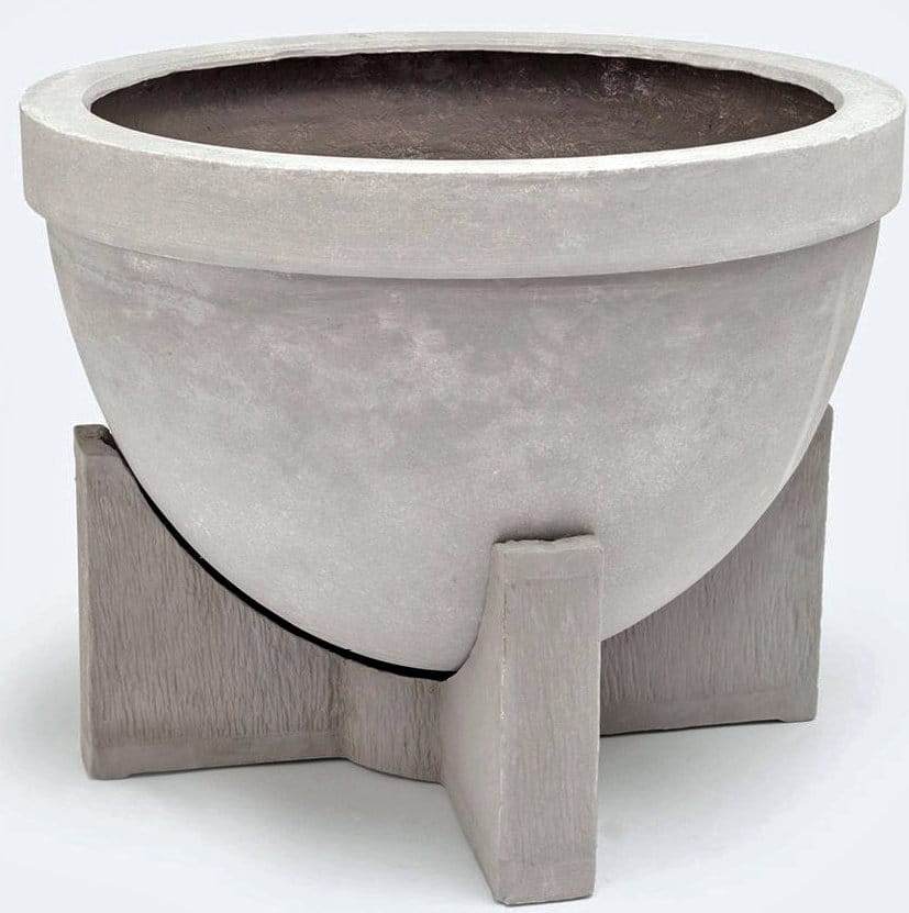 The image shows a large round concrete planter with a flat base and a wide opening It is placed on a wooden
