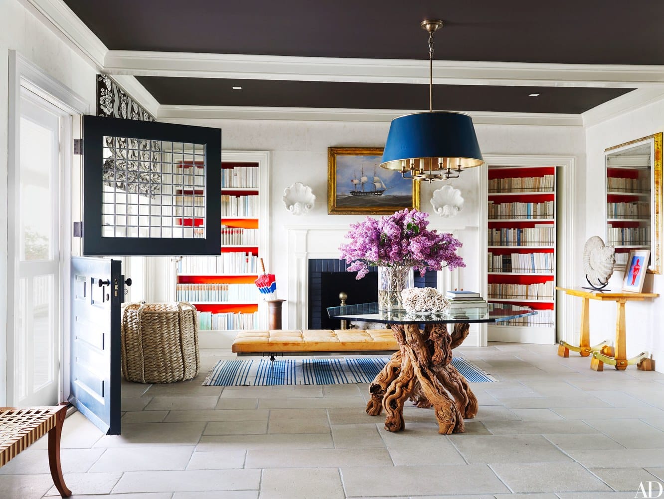 A spacious living room with a high ceiling and large windows featuring a dark wood floor white walls and a black chandelier