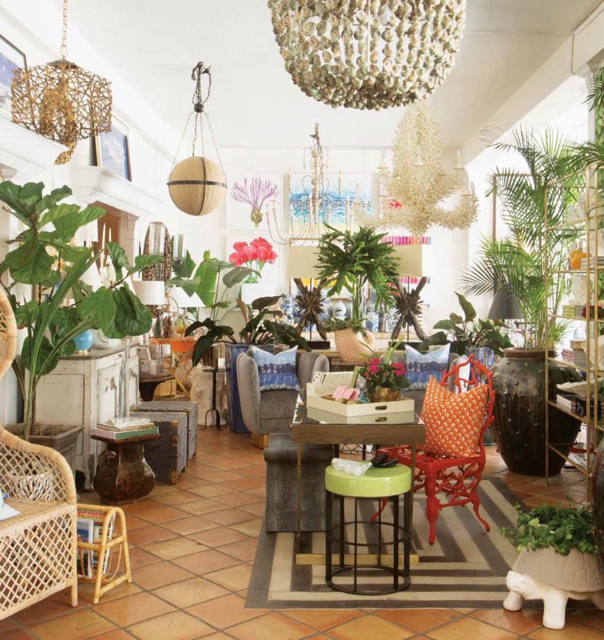 Luxurious store interior with a variety of furniture and decor items, including potted plants, hanging light fixtures, and various pieces of seating.