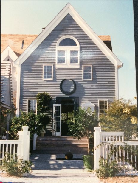 Large two-story house with a prominent front porch and white siding The house features a circular window above the entrance door and