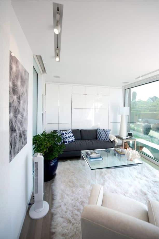 A modern, spacious living room with a large rug, white walls, and a contemporary sofa.