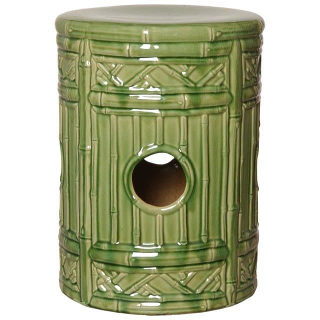 A green ceramic birdhouse with a hole for a bird to enter, placed on a surface.