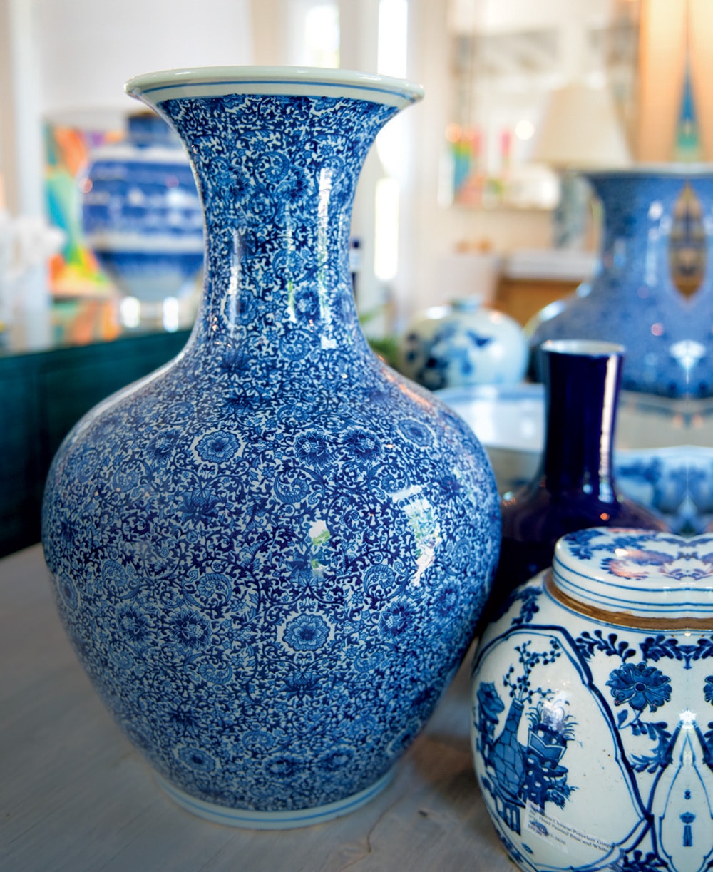 Blue and white vase on table with other vases in background