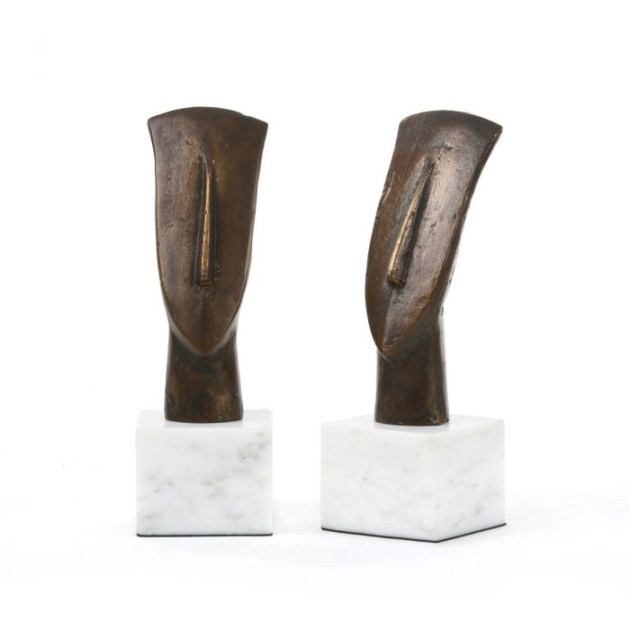 Two bronze statues of lost heads on pedestals, set against a white background.