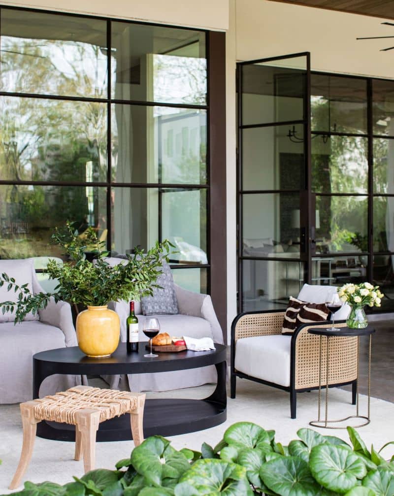 A spacious outdoor living room with a modern design featuring a large glass sliding door and a stylish patio furniture set including