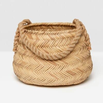 Small woven rattan basket with chevron design and twisted jute handles.