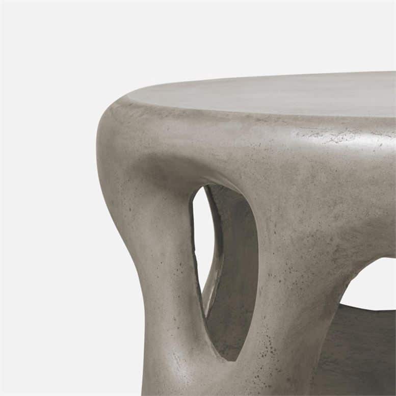 Outdoor sculpted concrete coffee table with smooth grey finish and unique handcrafted variations in color and texture.