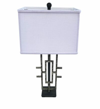 Table lamp with a rectangular white shade, mounted on a metal grate base with decorative lines.