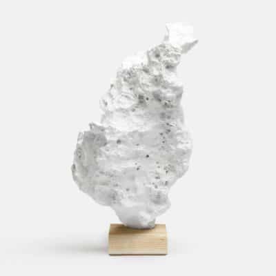 A large white hand cast faux coral sculpture on a banana leaf wrapped base, presented against a neutral background.