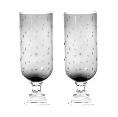 Hand crafted glass hurricane featuring an intricate star design, offering protection for candles while adding visual interest to any room.