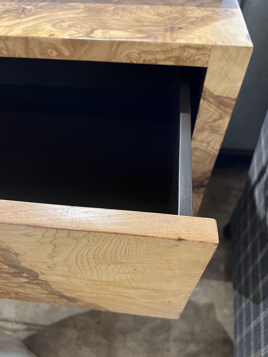 The image shows an open drawer on a wooden dresser, revealing its interior and brass hardware.