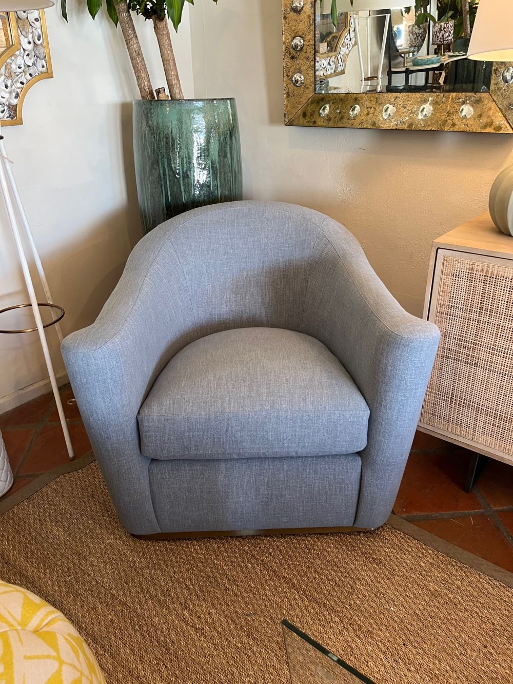 A modern, upholstered swivel chair with brass base.