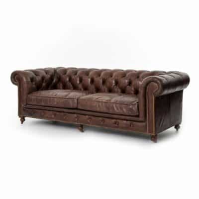 A dark brown leather sofa with antiqued brass nail heads and oak legs.