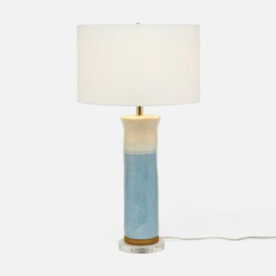 A stylish table lamp boasting a soft blue and cream color scheme on a lucite base, featuring a drum shade.