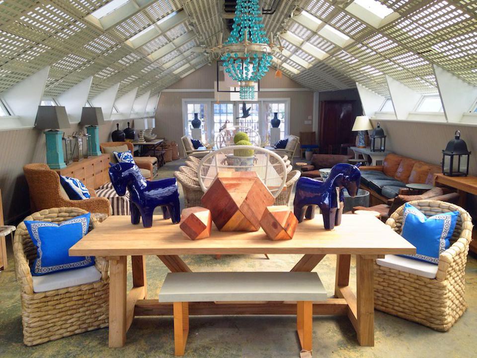 Modern living room with wooden furniture, blue accents, and chandelier hanging from ceiling.
