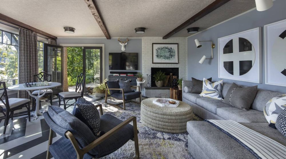 Modern living room with white walls, large windows, and stylish furniture including gray sofas, wooden coffee table, and black floor lamp.