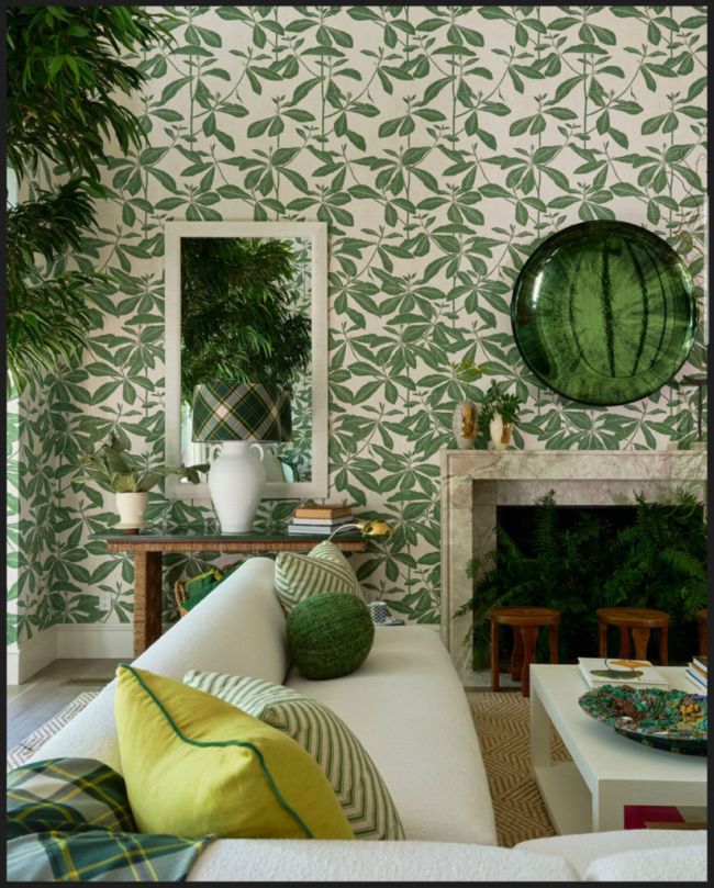 Luxurious sofa in tropical green room with leaf-patterned wallpaper.