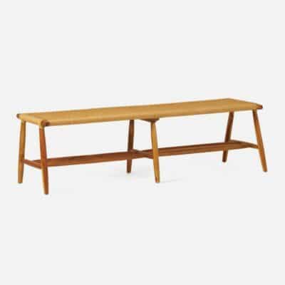 Long teak bench with woven seat in natural light stain finish, showcasing Scandinavian style and available in various sizes.