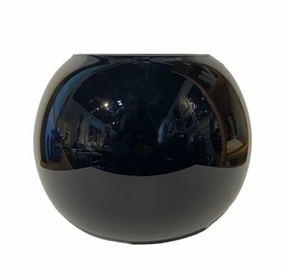 Close-up of vintage black glass bowl reflecting room lights, showcasing its smooth surface and elegant shape.