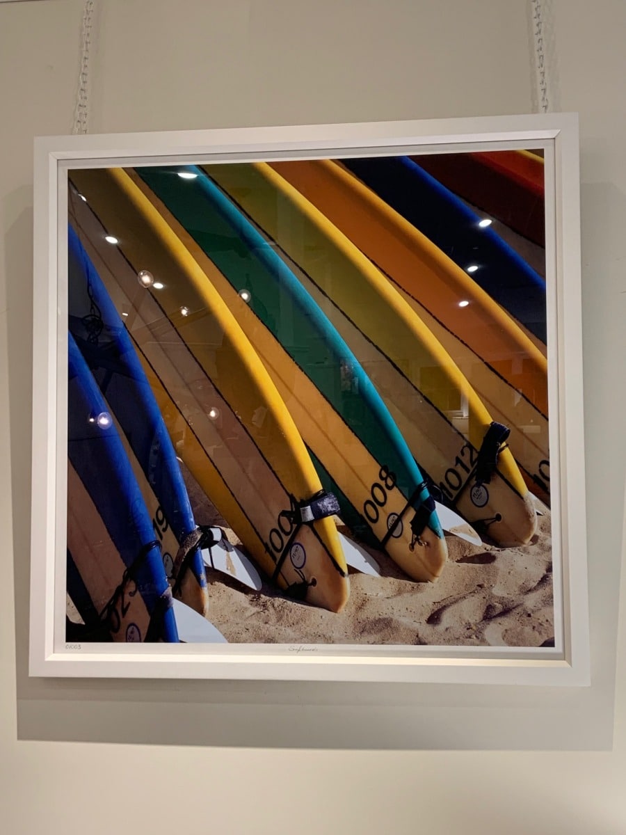 Close-up of colorful surfboards in white frame, showcasing vibrant hues and intricate details.