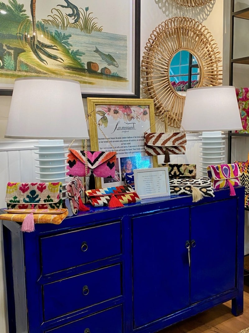 Bright blue cabinet showcasing colorful pillows and vibrant artwork in an inviting store setting.