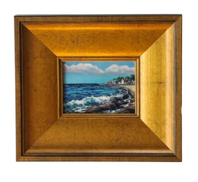 A close-up of a framed oil painting featuring a tranquil beach scene by Karen Neely in a luxurious gold frame.