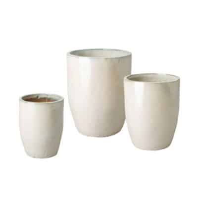 Close-up of tall pearl white ceramic planters, varying in size from small to large, showcasing their elegant simplicity.