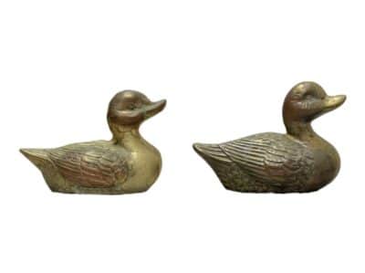 Close-up of two vintage brass ducks, side by side, showcasing intricate details.