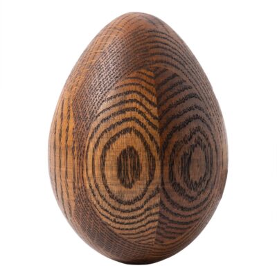 Close-up of vintage carved wood egg sculpture with intricate ring details in dark brown tones.