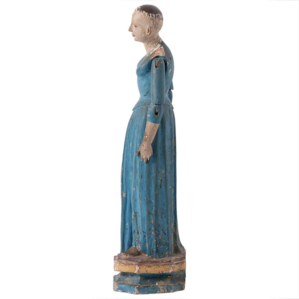 Antique painted wood cage doll with blue dress, round base, and visible patina.