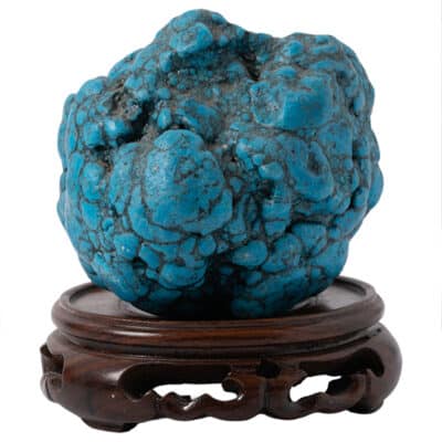 Blue turquoise stone on round wooden stand.