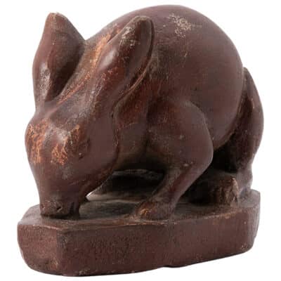 Close-up of vintage brown painted cast stone rabbit figurine on round base, with grass detail.