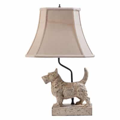 Close-up of vintage metal Scottie lamp with aged white paint, featuring a charming dog design on base.