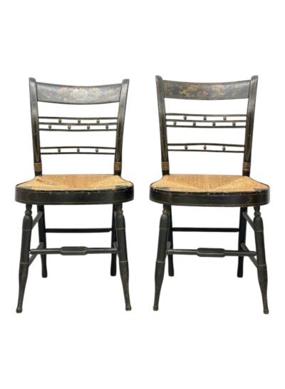 Pair of antique painted black side chairs, featuring stenciled bronze details and rush seats.