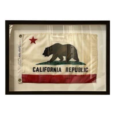 Vintage framed California state flag, mounted in a dark wood frame, showcasing its historical charm.
