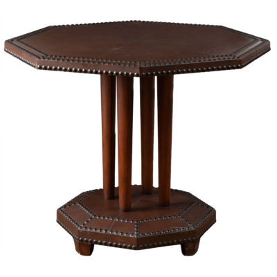 Close-up of an elegant vintage leather side table with intricate nailhead accents and an octagonal shape.