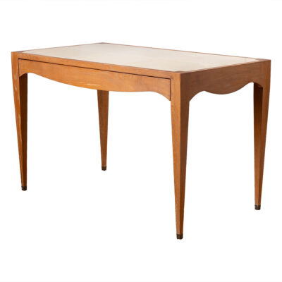 Front view of a vintage vellum top desk with aged light oak frame, featuring intricate details and brass foot caps.