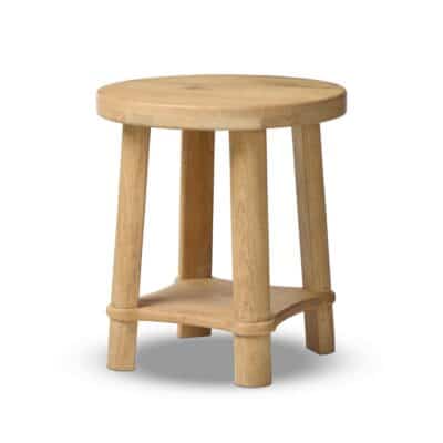 Close-up of a round natural wood stool with light finish and slightly angled legs, showcasing its solid construction and bottom shelf.