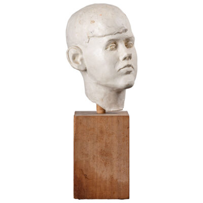 Close-up of vintage white cast plaster boy's head on aged wood block base.