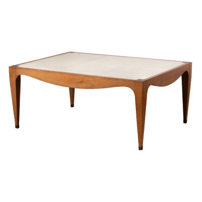 A vintage French style coffee table, featuring an aged vellum top on a light oak frame with elegant curved detail.