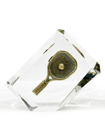 Close-up of Lucite encased vintage tennis brass buckle, showcasing intricate design and craftsmanship from the 1970s.