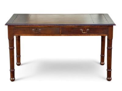 Close-up of antique English mahogany desk with embossed leather top and carved wood legs.